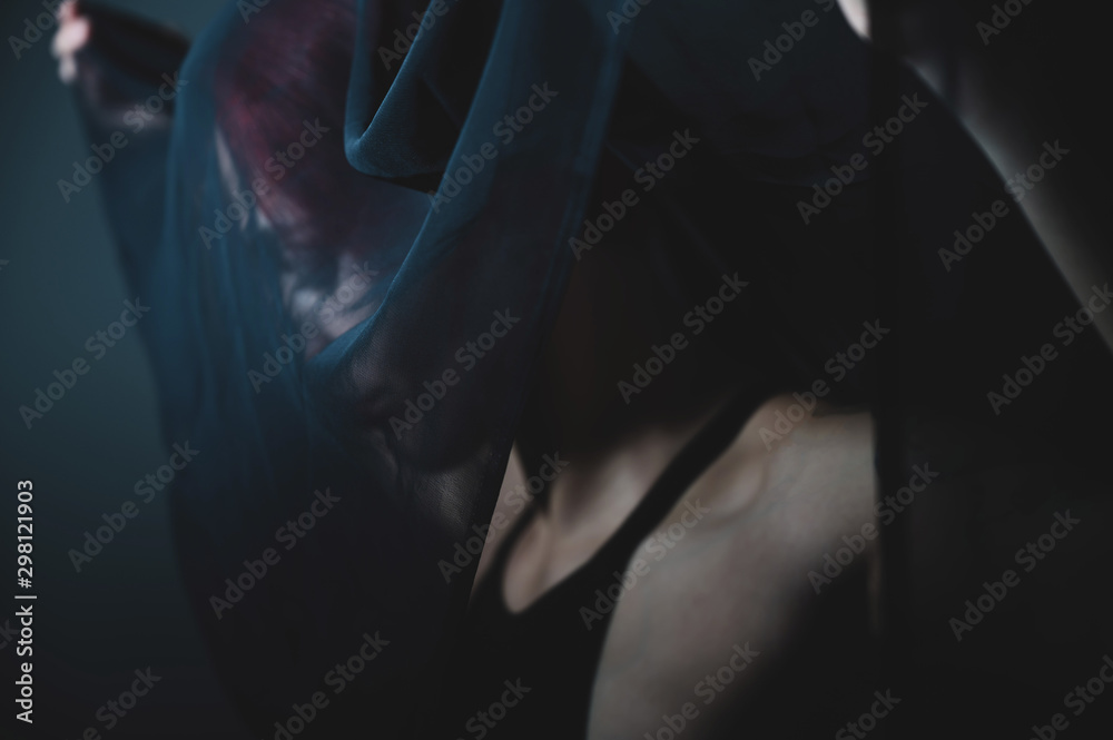 Sad woman in a black veil is standing in a dark studio. Halloween Dead Bride Costume. Profile of a grieving girl. Sad woman in a black veil is standing in a dark studio. Halloween Dead Bride Costume. Profile of a grieving girl.