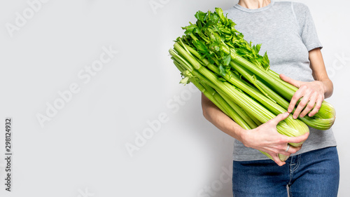 Woman holding green fresh celery. Healthy eating, vegetarian food, dieting and people concept