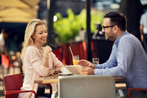 Happy couple using touchpad while relaxing in a cafe.