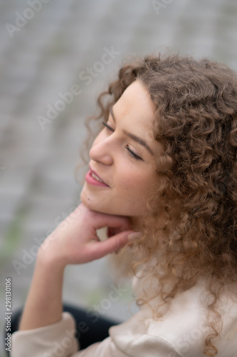 Profile view of young woman with curly hair resting her head on her hand