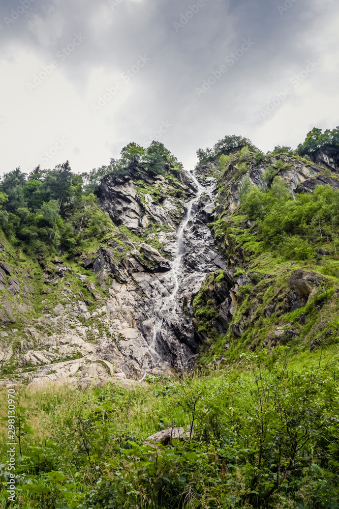 Waterfall between rocks flowing from mountain top.
