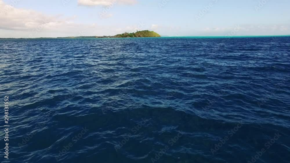 Tracking Shot of the Ocean and an Island Far Ahead Under Blue Sky and Clouds