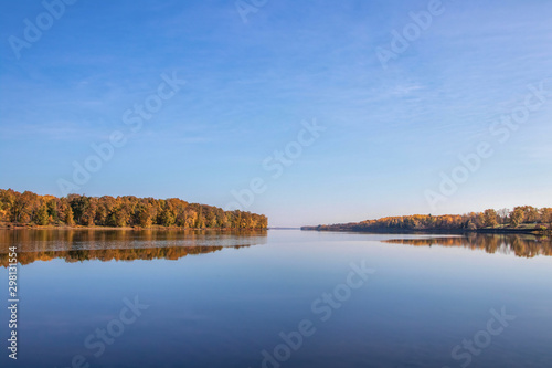 View looking down calm water at dawn with autumn trees and reflections nobody