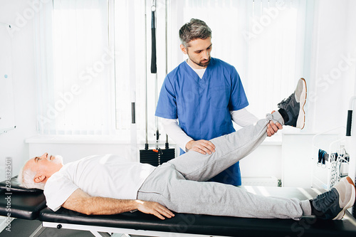 physiotherapist assisting a senior patient in recovery at wellness center.