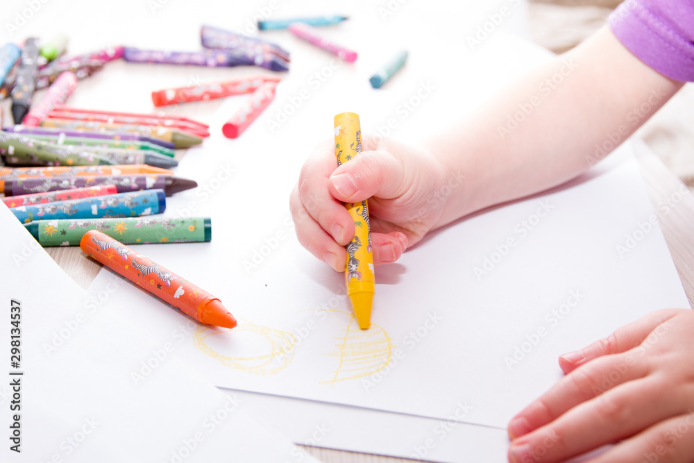 child draws the sun in crayons on paper child draws the sun in crayons on paper