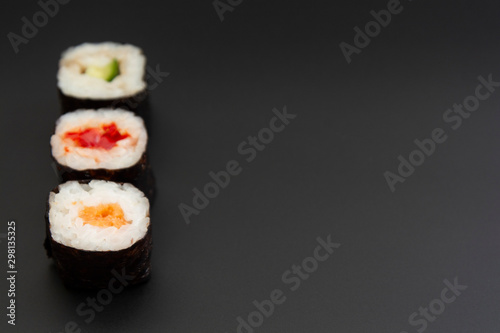 Set of three sushi rolls with fish, avocado and cheese on black background isolated. Traditional japanese food. Asian restaurant meals delivery. Copy space.
