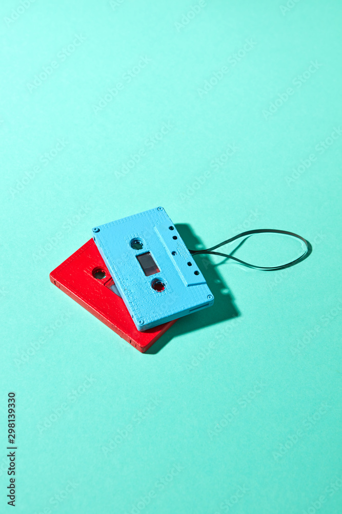 Red and blue retro cassette tapes with shadows on a turquoise color pantone background, copy space. Trend of minimalism. Red and blue retro cassette tapes with shadows on a turquoise color pantone background, copy space. Trend of minimalism.