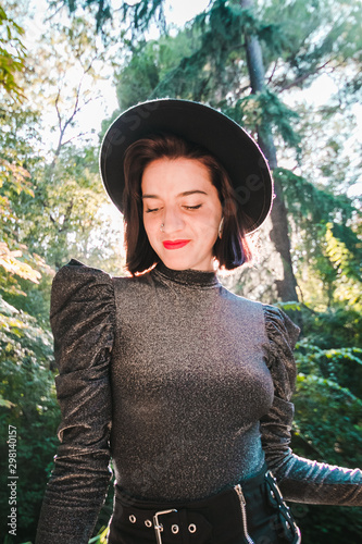 Street fashion concept - closeup portrait of a pretty hipster girl. Wearing  modern clothes with a hat. Artsy bohemian rock style. Toned style instagram filters in nature background