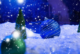 Christmas background with Christmas balls on snow over fir-tree, night sky and moon. Shallow depth of field. Christmas background. Fairy tale. Macro. Artificial magic dreamy world.