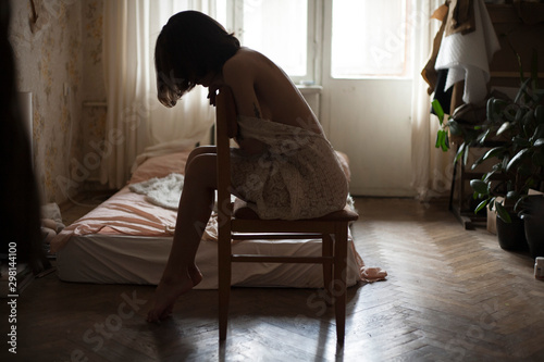 girl in a dress sits on a chair in the background of her room