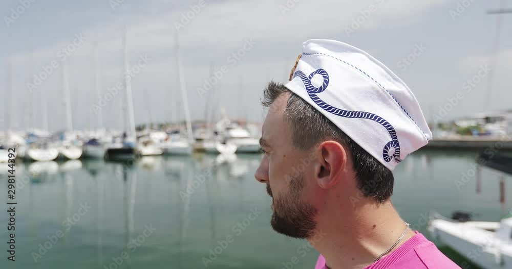 A bearded man in a sailor's cap walks along the pier. A bearded man in a sailor's cap walks along the pier.