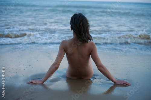 naked girl sitting by the sea photo