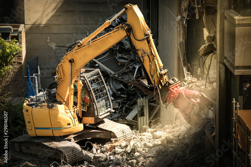 Heavy machinery surrounded with dust  cloud taking down an old building 