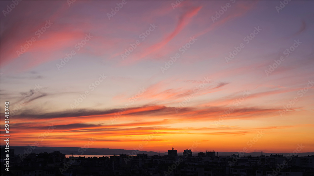 Beautiful sunset afterglow over a city. Vivid sky of golden and orange colors during sundown. Scenic skyscape at the sunset.