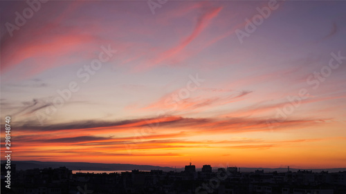 Beautiful sunset afterglow over a city. Vivid sky of golden and orange colors during sundown. Scenic skyscape at the sunset.