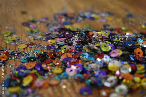 Pile of Glitter and sequins on brown wood table. © Lindsey