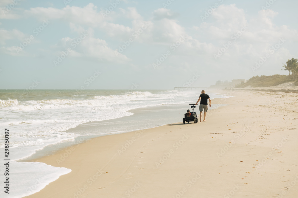 Grandfather pulling his grandson in a wagon on the beach Grandfather pulling his grandson in a wagon on the beach