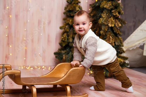 a boy near the Christmas trees on a sled, Christmas lights, rejoices and smiles, plays. holiday and vacation