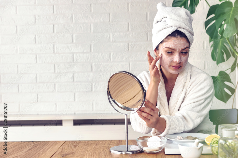 Young woman applying face mask at home. Natural Skin Care Routine. Cleaning face with natural cosmetics. Young woman applying face mask at home. Natural Skin Care Routine. Cleaning face with natural cosmetics.