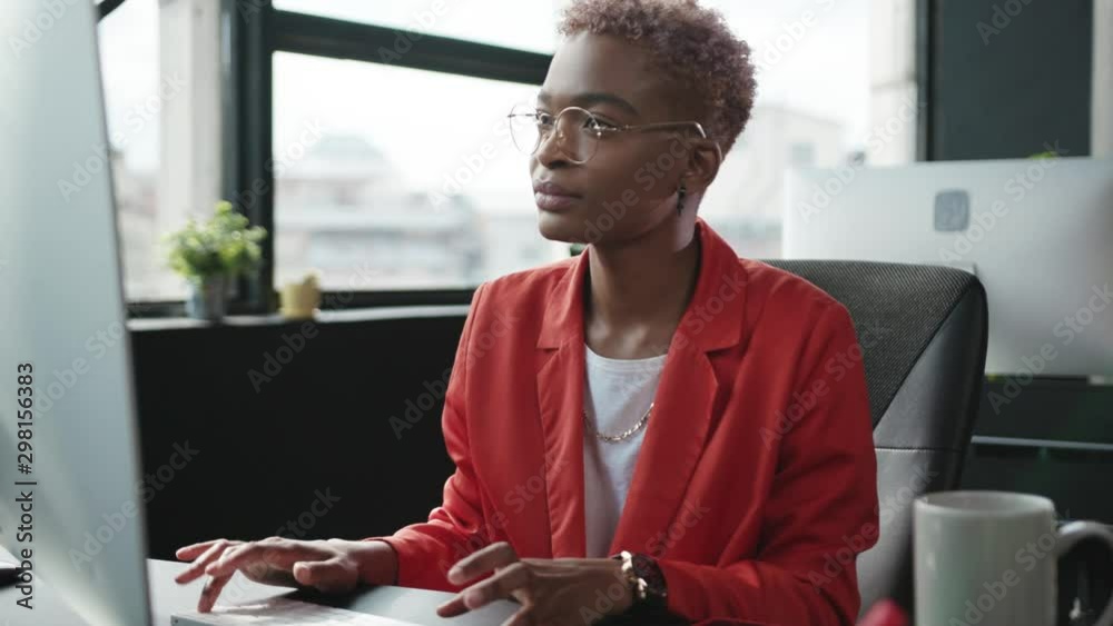Attractive afro-american young woman in business attire working on modern personal computer in contemporary office company. Business person portrait.