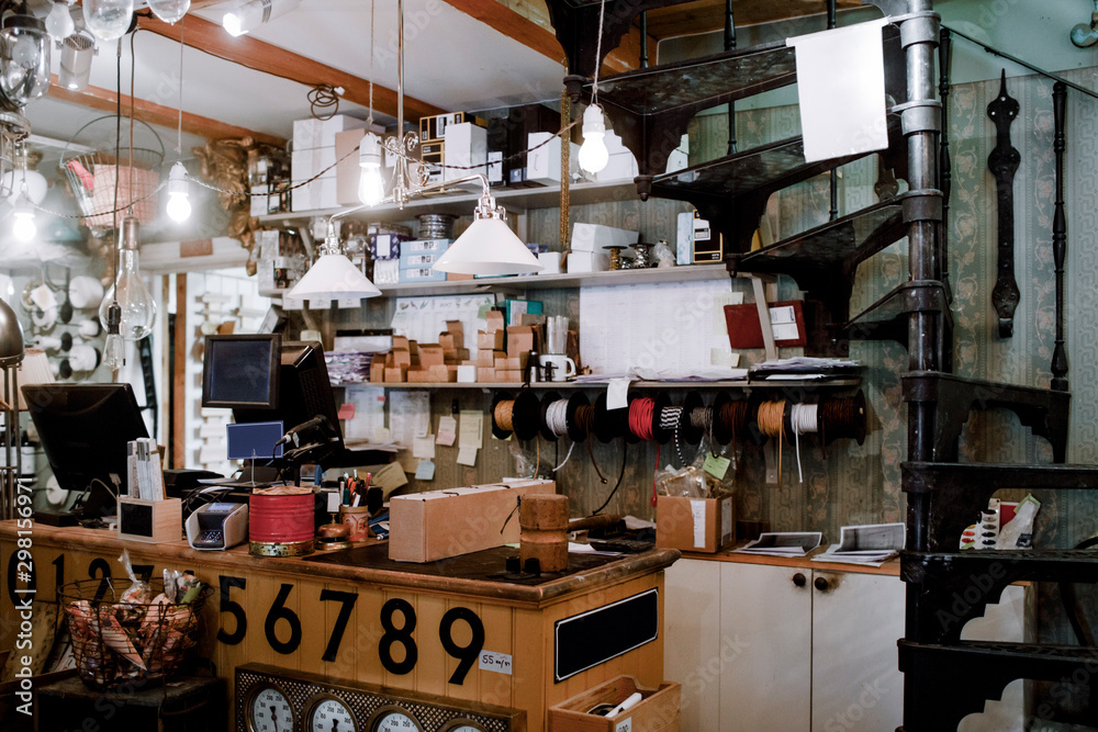 Illuminated pendant lights hanging over checkout counter against various equipment at hardware store Illuminated pendant lights hanging over checkout counter against various equipment at hardware store
