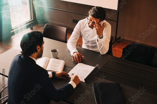 High angle view of male lawyer showing file to mature stressed client at board room in law office