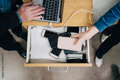 High angle view of female student collecting phone in drawer during exam in school