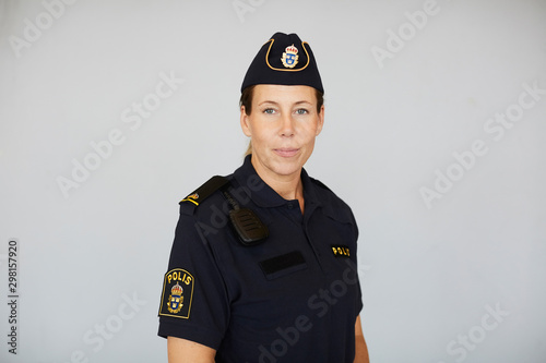 Portrait of policewoman in uniform standing against white background photo