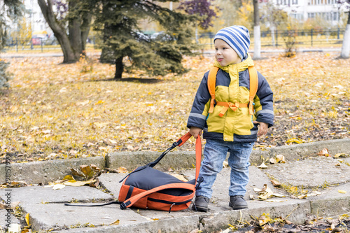 Obraz na plátně little hooligan boy dragged away his mother's backpack and make grimace at her i