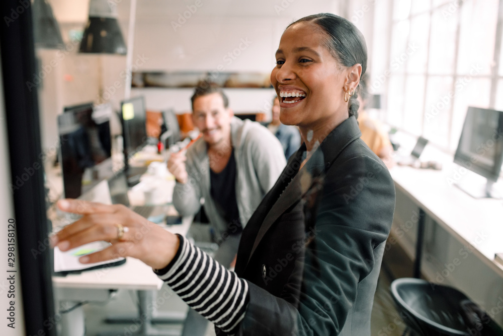Smiling businesswoman discussing with coworker seen through glass at office Smiling businesswoman discussing with coworker seen through glass at office