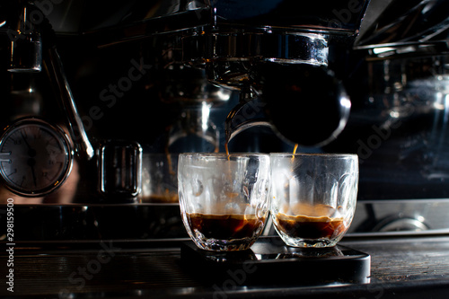 coffee machine makes double espresso in glasses at night, the process of making coffee, close-up