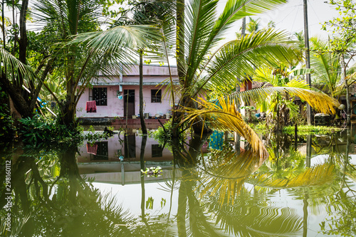 Fototapeta Naklejka Na Ścianę i Meble -  Traditional house in the Kerala backwaters in the lush jungle along the canal, Alappuzha - Alleppey, India