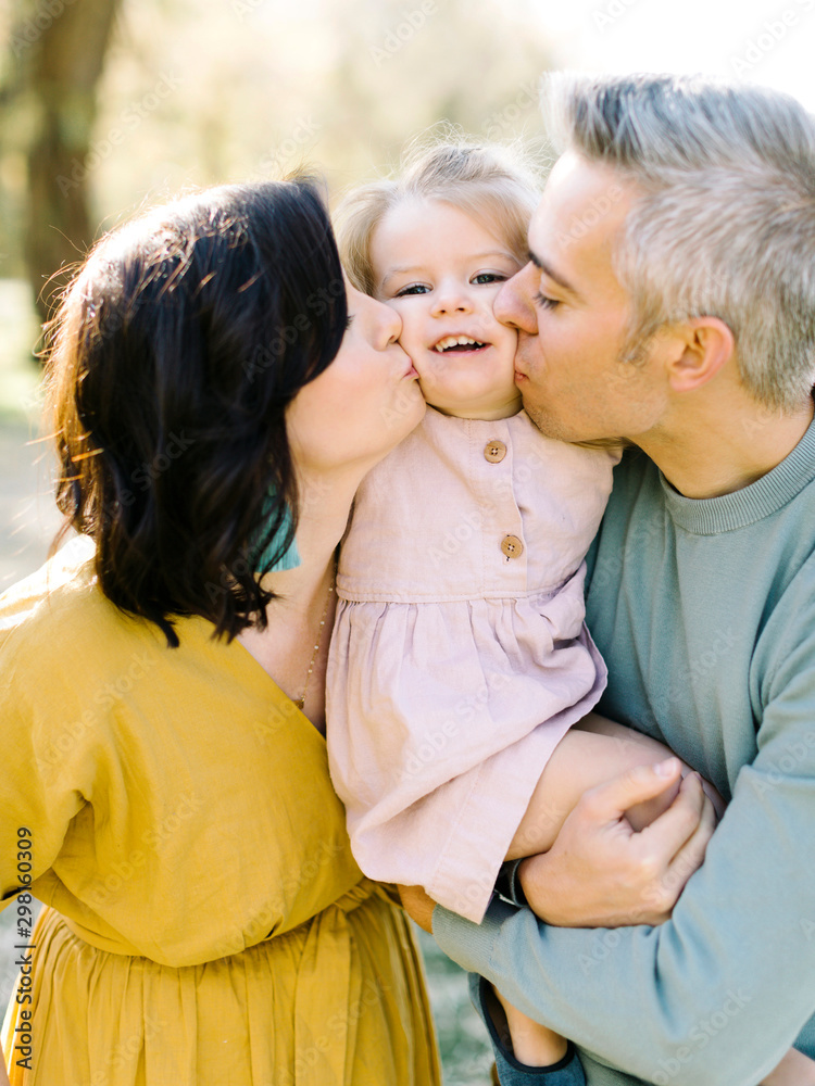 Parents kissing their daughter's cheeks Parents kissing their daughter's cheeks