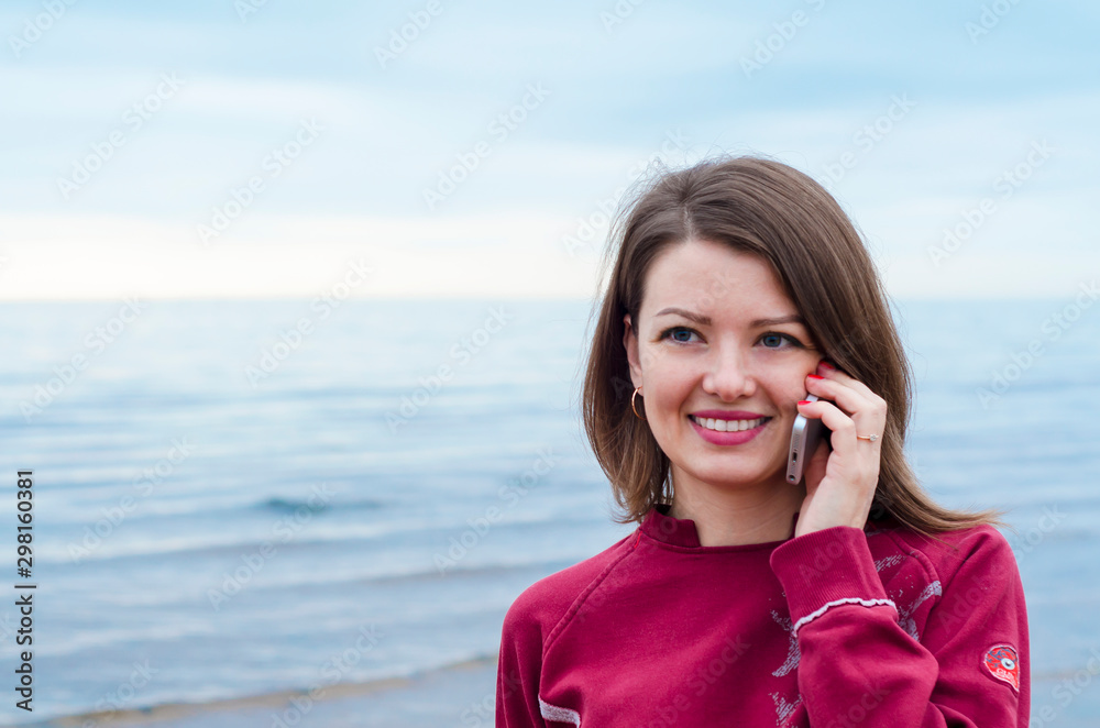 bright portrait of beautiful girl talking on the phone and smiling outdoors by the sea, ocean. bright portrait of beautiful girl talking on the phone and smiling outdoors by the sea, ocean.