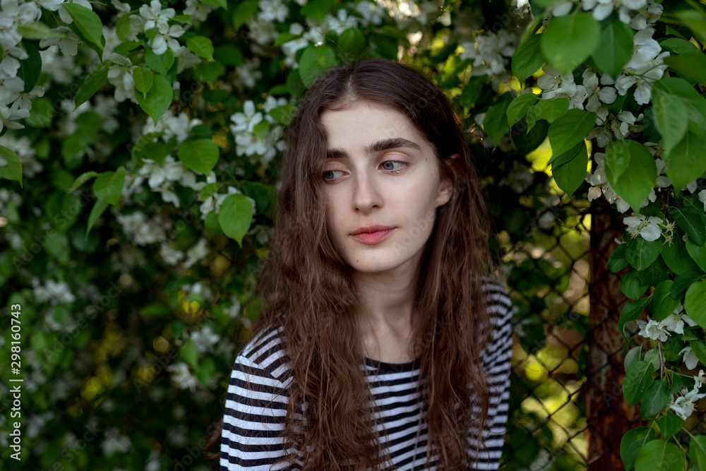 Young woman wearing stripes by white flowers Young woman wearing stripes by white flowers
