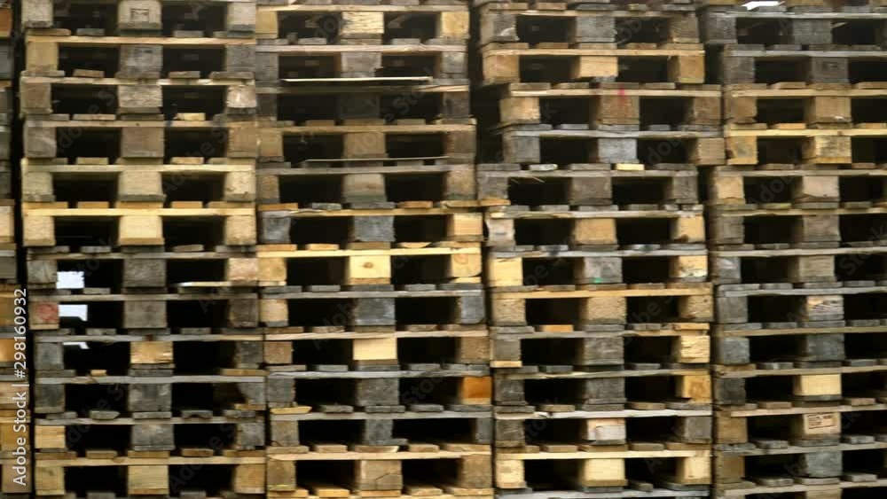 Close up of stacked wooden pallets on a storage place. Pan right to left
