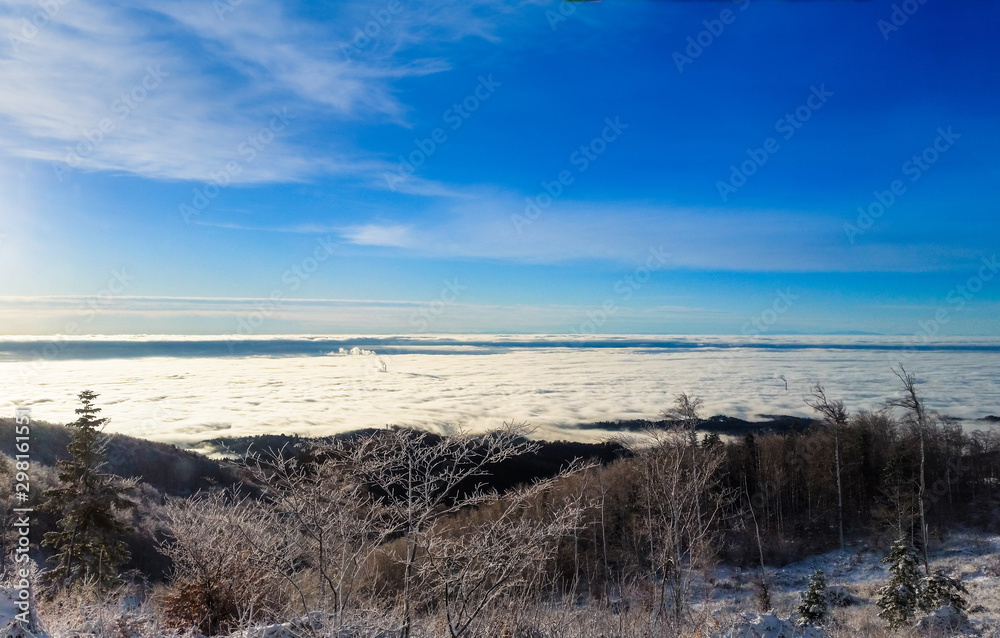 Winter landscape with trees and blue sky. Find a smoking chimney in the clouds. Sljeme, Zagreb, Croatia