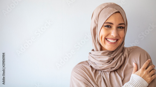 Portrait of islamic woman smiling. Pretty muslim girl. Beautiful asian muslimah woman model posing on grey wall studio. Portrait Of Arab Beauty.