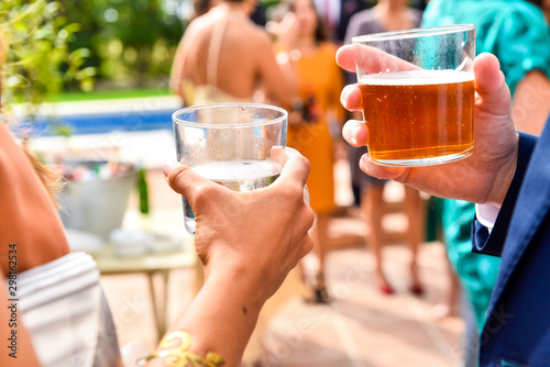 Guests at an event hold glasses with drinks and cold beers while they talk about business and social relationships.