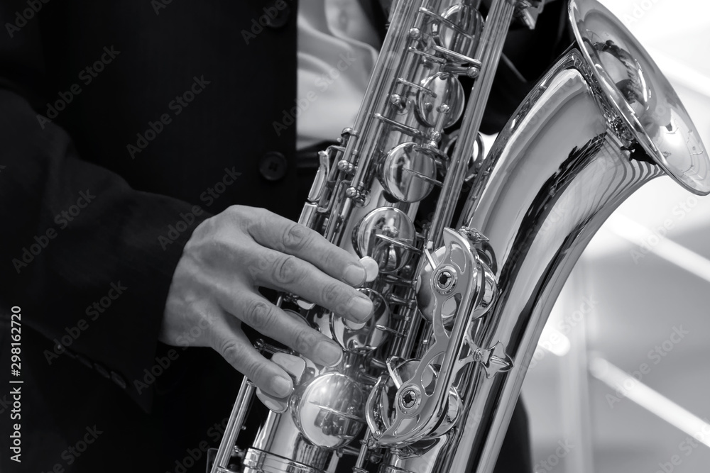 Obraz premium A man in a strict dark suit plays the saxophone