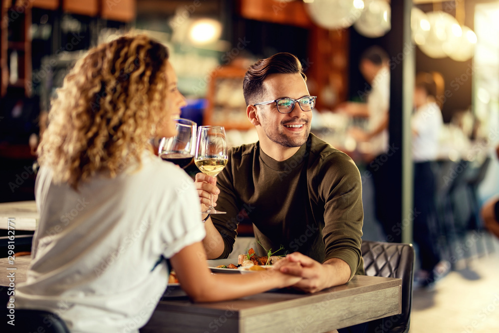 Happy couple in love enjoying in glass of wine during lunch.