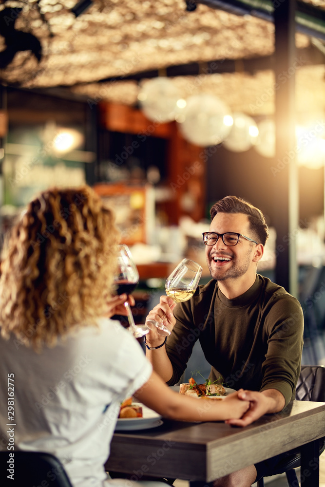 Cheerful man having fun while drinking wine with his girlfriend in a restaurant.