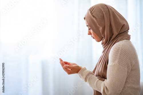 Young Woman Praying. Young Muslim woman praying, indoors. Young muslim woman in beige hijab and traditional clothes praying for Allah, copy space. Arab Muslim woman praying photo