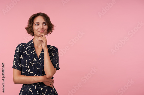 Fotografie Studio shot of attractive brunette woman with short haircut looking dreamily asi