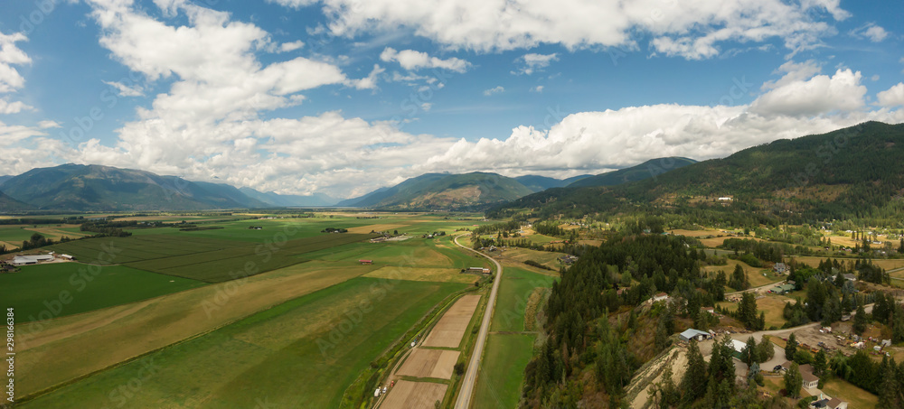 Aerial Panoramic View of Small Town, Creston, during a sunny and cloudy summer day. Located in the Interior of British Columbia, Canada.