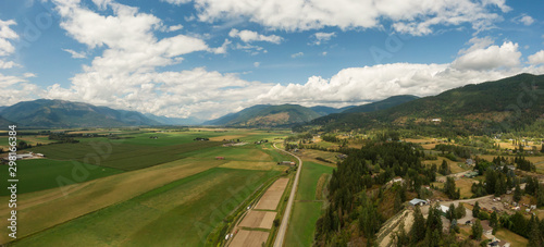 Aerial Panoramic View of Small Town, Creston, during a sunny and cloudy summer day. Located in the Interior of British Columbia, Canada.