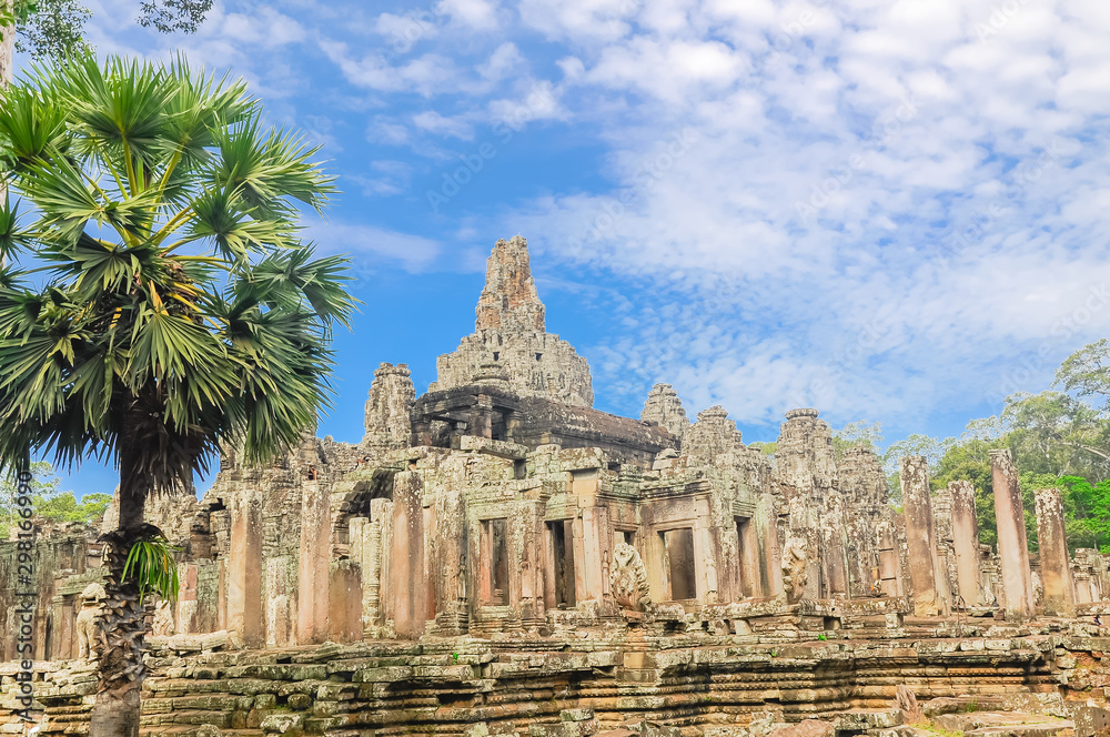 Ancient Angkor Wat temple and palm trees under summer cloud blue sky