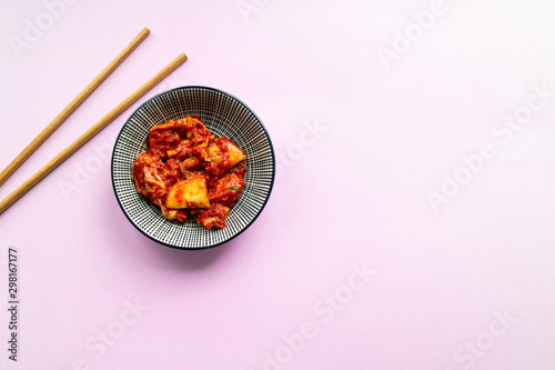 Korean spicy kimchi with chopsticks on pink background. Top view.