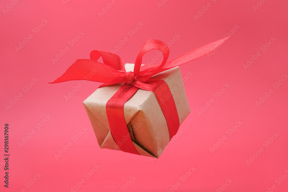 Gift box with red ribbon on red background. zero gravity. levitation. milimalism. Concept sales, shopping, christmas holidays and birthday Gift box with red ribbon on red background. zero gravity. levitation. milimalism. Concept sales, shopping, christmas holidays and birthday