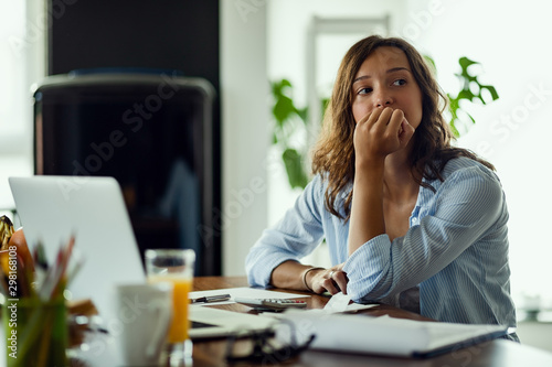 Pensive woman feeling worried while working on home finances. photo